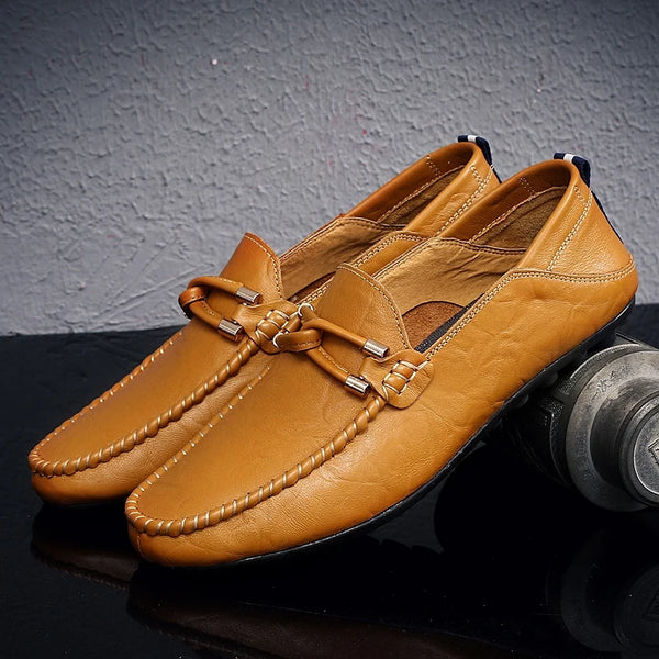 Pair of tan loafers on a reflective surface with a gray textured background