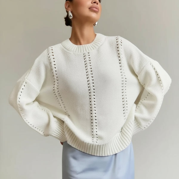 Woman wearing a white sweater with a textured pattern against a neutral background