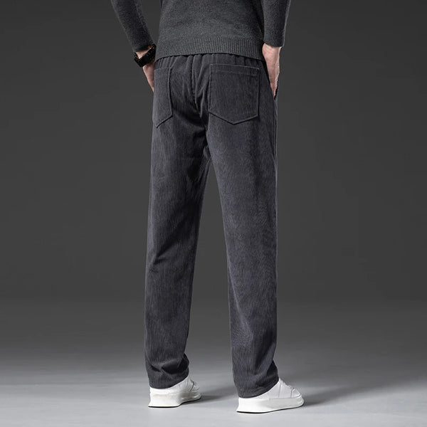 Person wearing dark gray jogger pants on a gray background