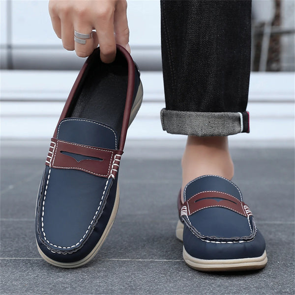 Person wearing navy blue loafers with brown accents on a blurred street background