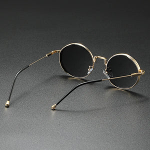 Round sunglasses with gold frames and black lenses on a gray background