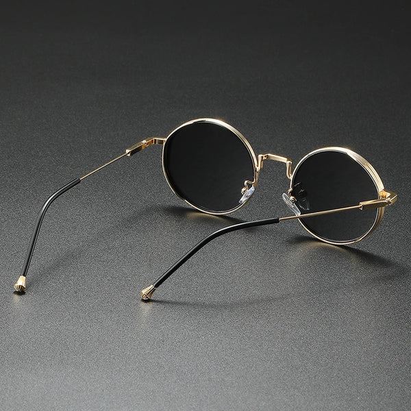 Round sunglasses with gold frames and black lenses on a gray background