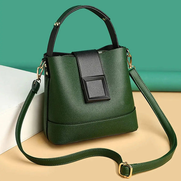 Green handbag with a black strap on a beige surface against a green background