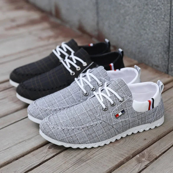 Pair of gray sneakers with white laces on a wooden surface