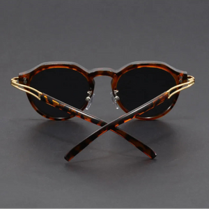 Crossed sunglasses with tortoiseshell frame and dark lenses on a gray background