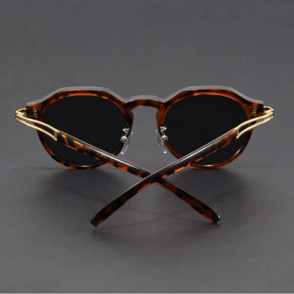 Crossed sunglasses with tortoiseshell frame and dark lenses on a gray background