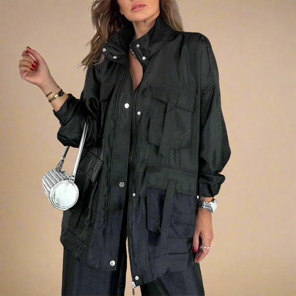 Woman wearing a black jacket with multiple pockets indoors.
