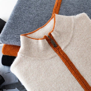 Folded knit sweater with orange zipper and trim on a gray surface