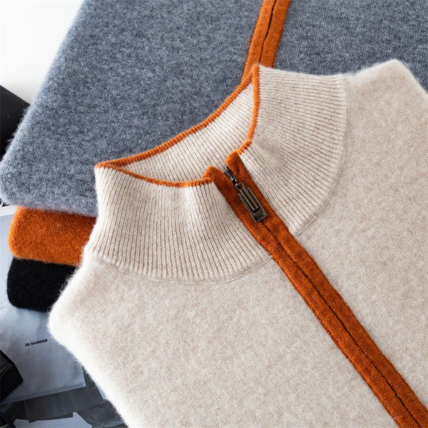 Folded knit sweater with orange zipper and trim on a gray surface