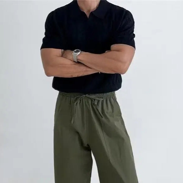 Person wearing a white textured short-sleeve shirt and dark pants on a gray background