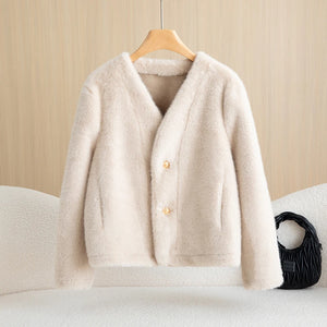 Beige cardigan on a wooden hanger against a beige wall.