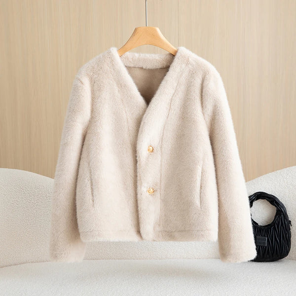 Beige cardigan on a wooden hanger against a beige wall.