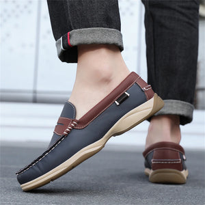 Brown and black loafers worn with rolled-up jeans on a blurred background