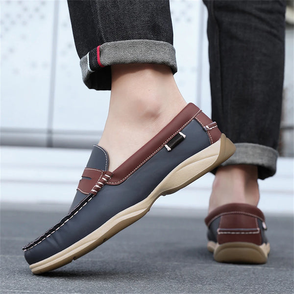 Brown and black loafers worn with rolled-up jeans on a blurred background