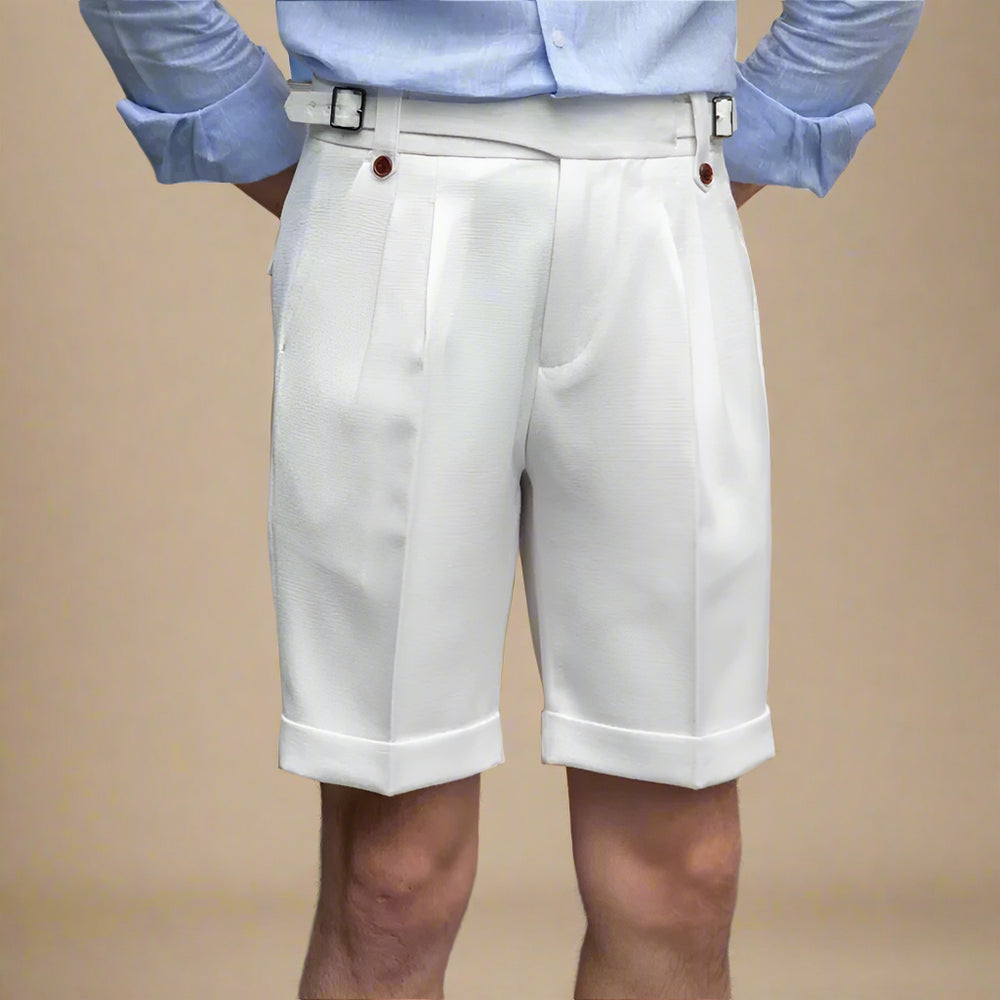 Person wearing a light blue shirt and white shorts against a beige wall.