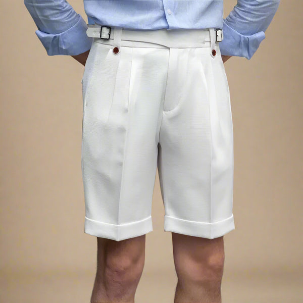 Person wearing a light blue shirt and white shorts against a beige wall.