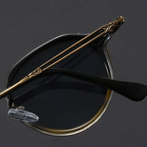 Vintage-style eyeglasses with decorative arm on a dark background