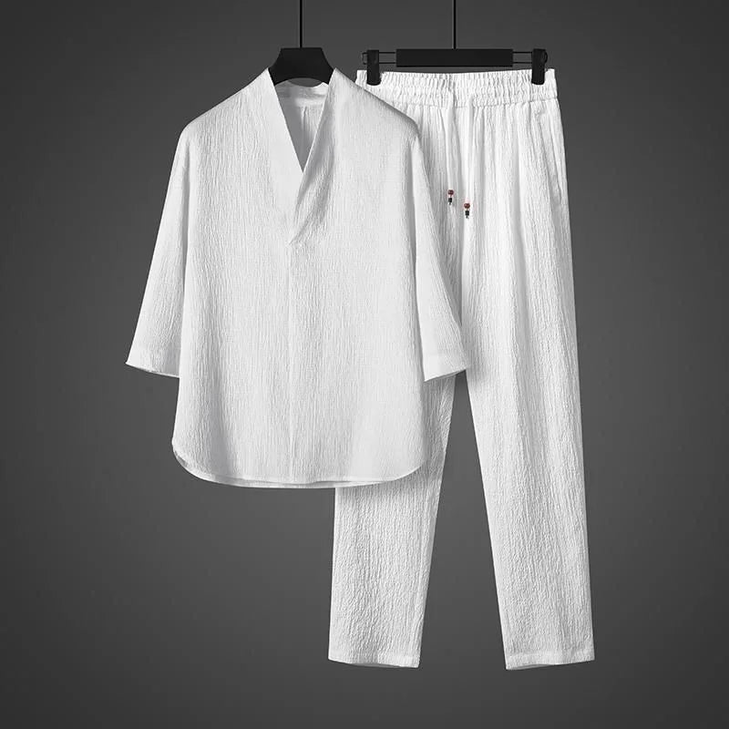 White shirt and pants set on hangers against a gray background