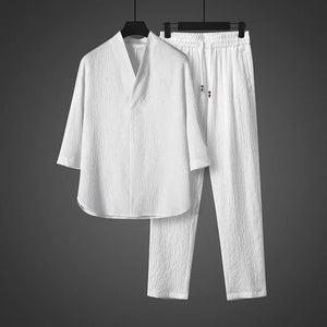 White shirt and pants set on hangers against a gray background