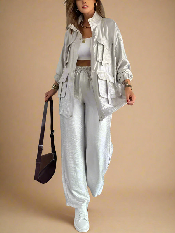 Woman in a stylish outfit with a jacket, pants, and sneakers in a modern interior setting.