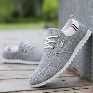 Gray casual shoes with white soles on a wooden surface