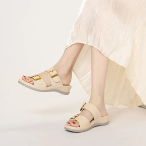 Beige sandals worn with a light-colored skirt on a white background