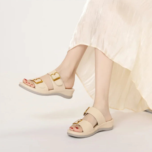 Beige sandals worn with a light-colored skirt on a white background