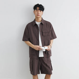 Man wearing a brown shirt and shorts set against a plain background