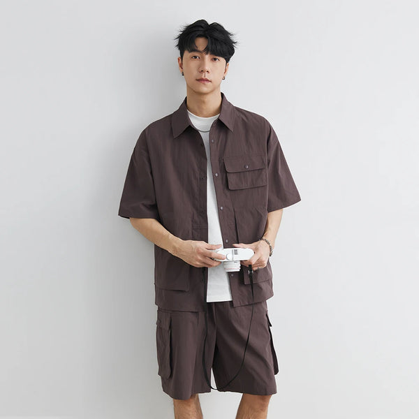 Man wearing a brown shirt and shorts set against a plain background