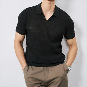 Person wearing a black textured polo shirt and brown pants against a light gray background