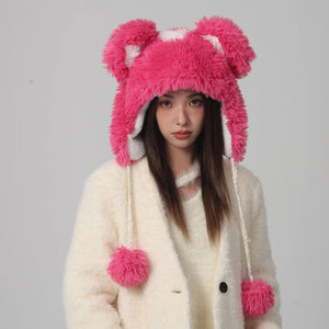 Person wearing a pink fluffy hat with animal ears on a gray background