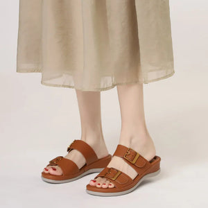 Brown sandals worn with a beige skirt on a plain background