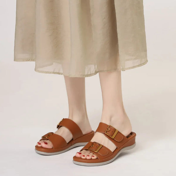 Brown sandals worn with a beige skirt on a plain background