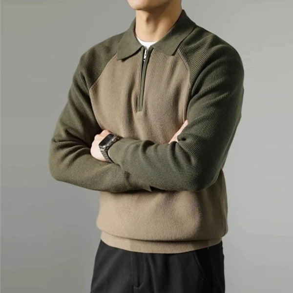 Person wearing a green and beige sweater with a plain background