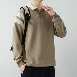 Person wearing a beige pullover with striped sleeves against a plain background