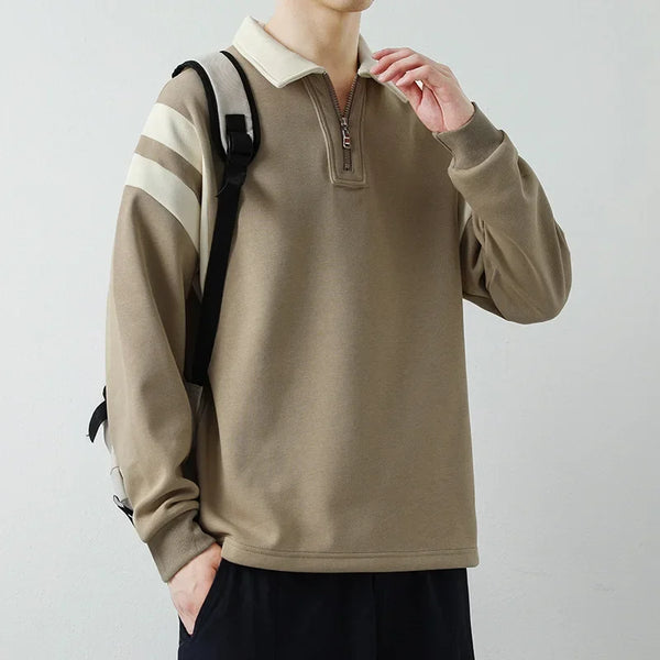 Person wearing a beige pullover with striped sleeves against a plain background