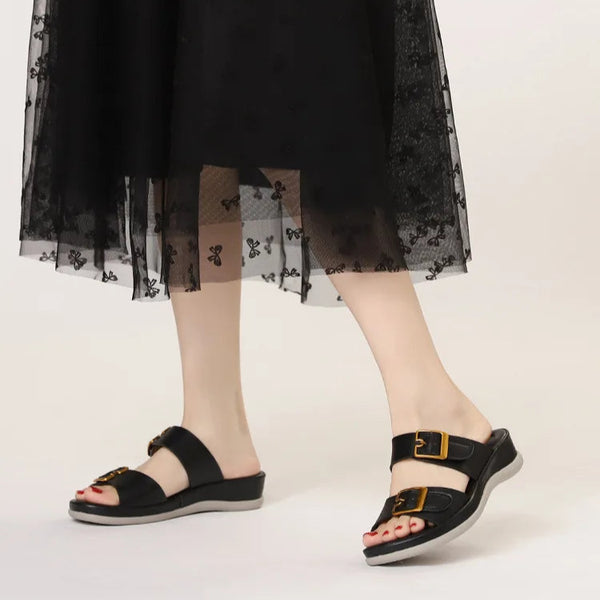 Person wearing black sandals with a sheer black skirt on a white background