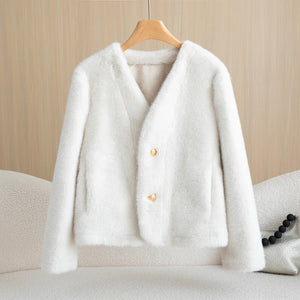 White fluffy cardigan on a wooden hanger against a beige background