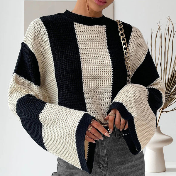 Person wearing a black and white striped sweater with a neutral background