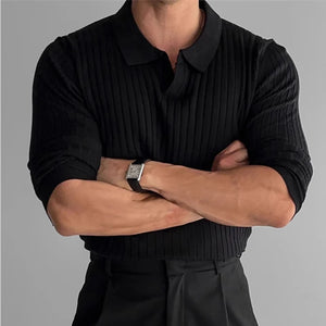 Person wearing a black ribbed sweater with arms crossed on a gray background