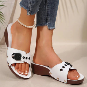 White sandals with brown soles worn by a person, with a blurred background