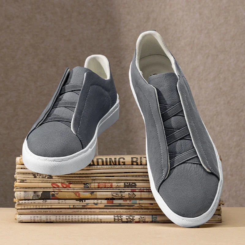 Gray slip-on sneakers on a stack of newspapers with a brown background