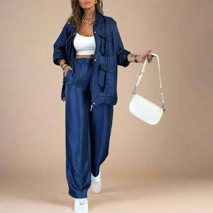 Woman in a blue outfit holding a white handbag in an indoor setting.