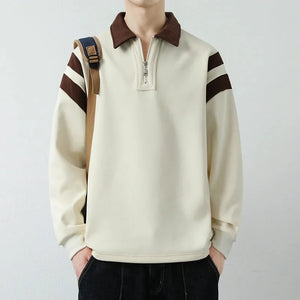 Person wearing a cream-colored sweater with brown accents on a plain background