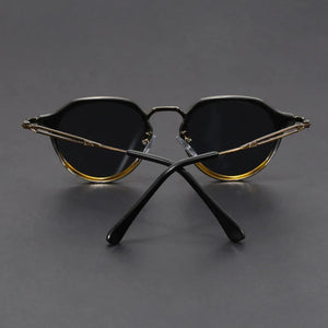 Pair of sunglasses with gold and black frames on a gray background
