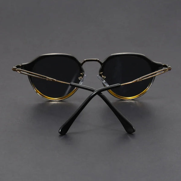 Pair of sunglasses with gold and black frames on a gray background
