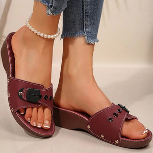 Maroon sandals worn with denim jeans on a neutral background