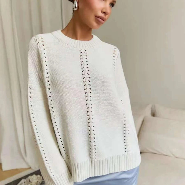 Woman wearing a white sweater with lace details against a neutral background