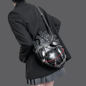 Person wearing a unique black backpack with chain details on a plain background