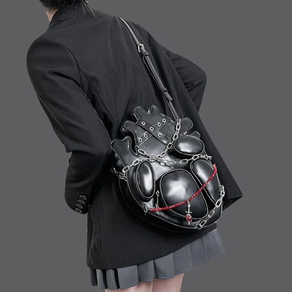 Person wearing a unique black backpack with chain details on a plain background